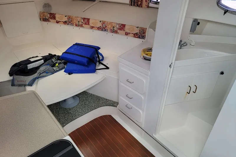 Slide: The Image of 2000 Stamas 310 Express cabin interior with table, life jackets, and compact kitchenette. - 18