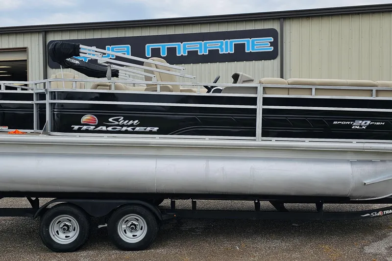 The Image of 2024 Sun Tracker SportFish 20 DLX pontoon boat on trailer outside marine shop. - 0