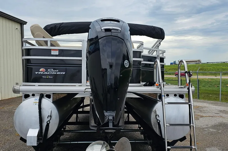 Slide: The Image of 2024 Sun Tracker SportFish 20 DLX pontoon boat with powerful outboard motor, docked outdoors. - 2