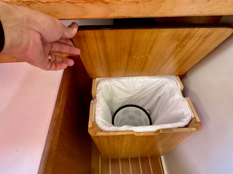 Slide: The Image of Hand opening wooden cabinet with trash bin inside on Catalina 36, 2005 model. - 47