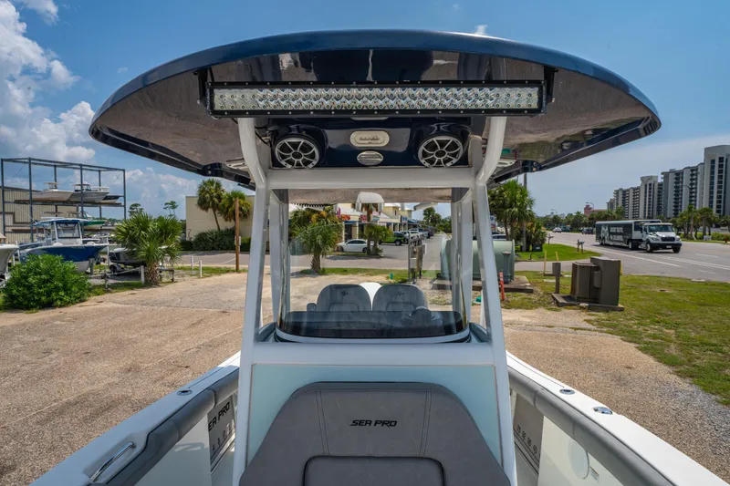 Slide: The Image of 2021 Sea Pro 239 Center Console boat with T-top and speakers, parked near a road. - 21