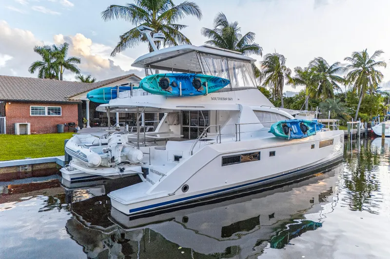 Slide: The Image of 2018 Leopard 51 Powercat yacht docked, featuring kayaks and palm trees in the background. - 103
