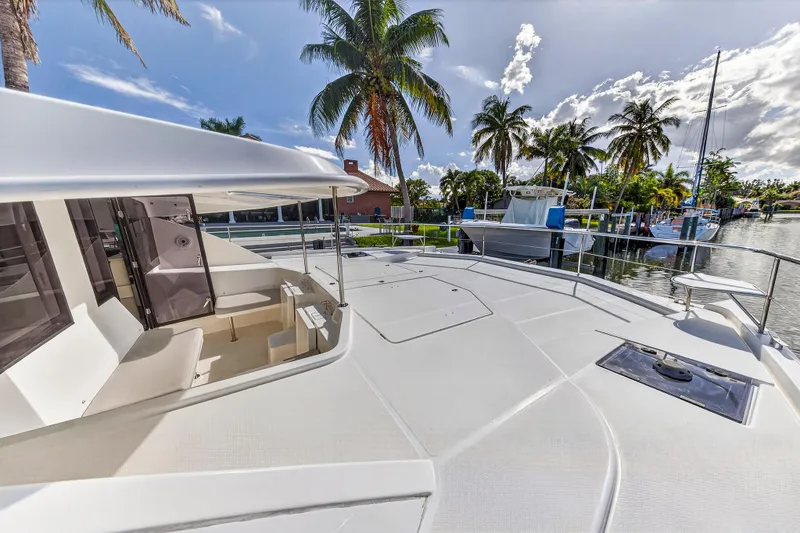 Slide: The Image of 2018 Leopard 51 Powercat yacht docked, featuring spacious deck and tropical palm trees. - 46