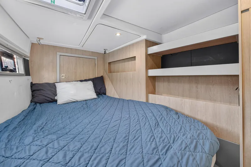 Slide: The Image of Cozy cabin interior of 2018 Leopard 51 Powercat with blue bedding and wooden shelves. - 97