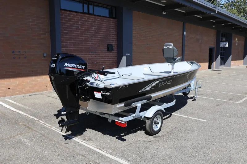 Slide: The Image of 2025 Lund SSV-18 boat with Mercury engine on trailer, parked outside a building. - 11