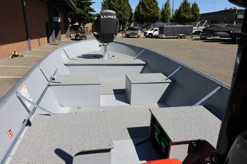 Slide: The Image of 2025 Lund SSV-18 boat interior with seating and storage, parked outdoors. - 15