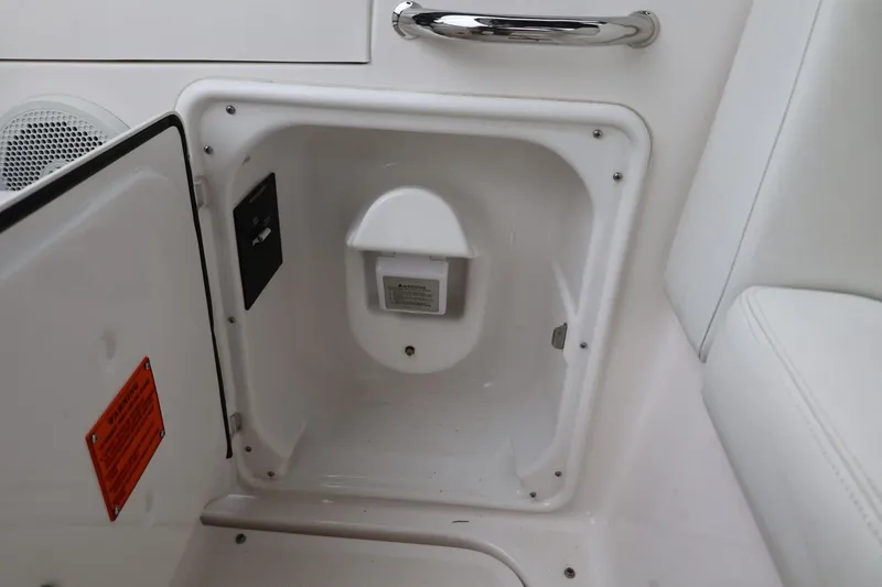 Slide: The Image of 2014 Regal 30 Express boat storage compartment with white interior and safety labels. - 19