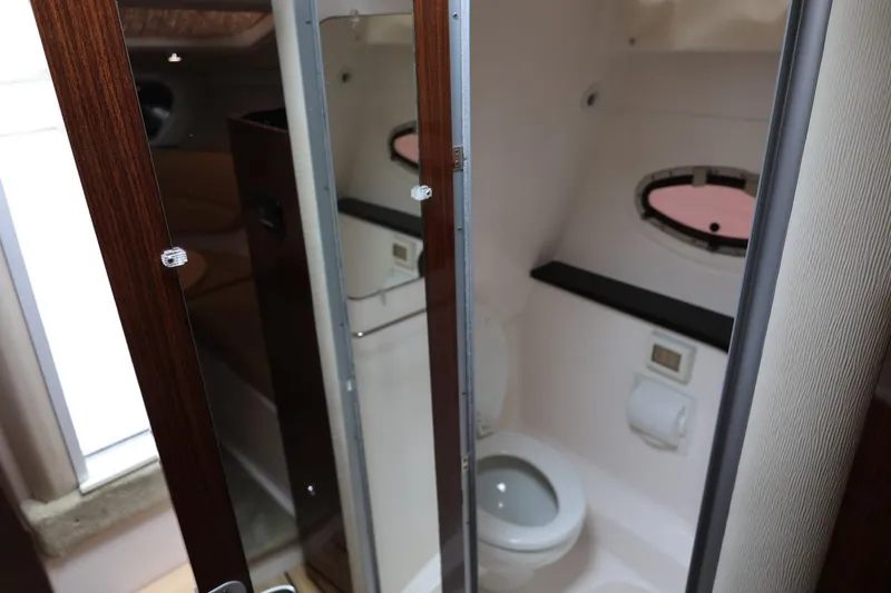 Slide: The Image of 2014 Regal 30 Express boat bathroom with wooden door and porthole window. - 35