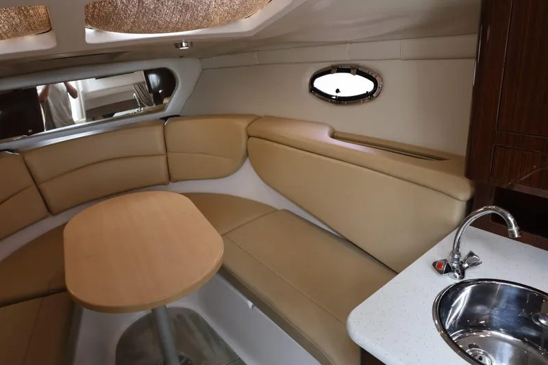 Slide: The Image of 2014 Regal 30 Express cabin interior with beige seating, wooden table, and compact kitchenette. - 40