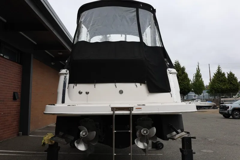 Slide: The Image of 2014 Regal 30 Express boat with black canopy, rear view in a parking area. - 6