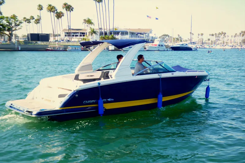 Slide: The Image of 2018 Chaparral 267 SSX boat cruising in a sunny marina with palm trees. - 2