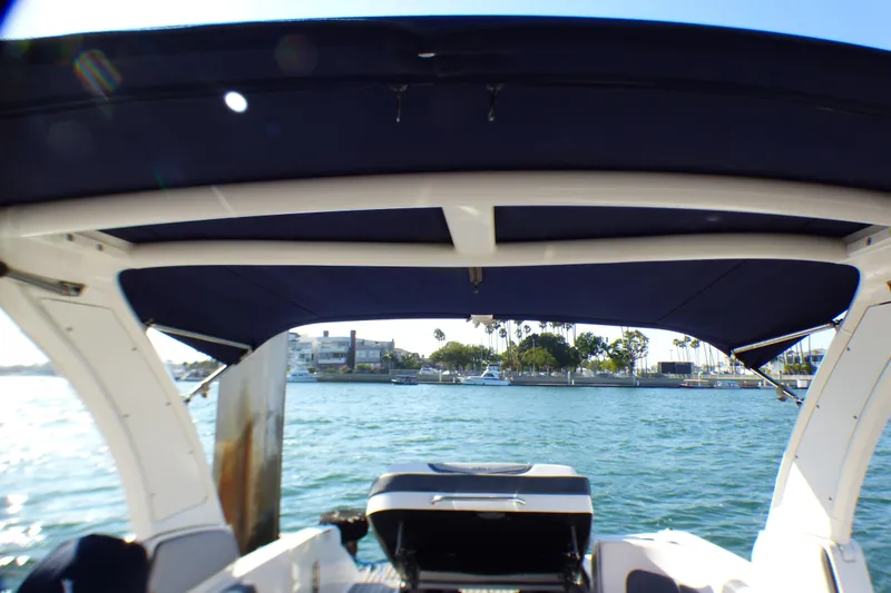 Slide: The Image of 2018 Chaparral 267 SSX boat with canopy, docked near waterfront homes. - 27