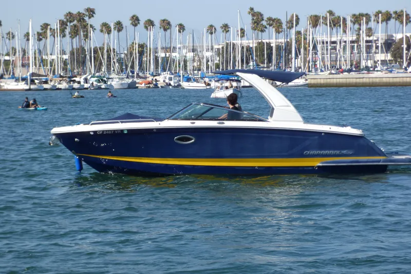 Slide: The Image of 2018 Chaparral 267 SSX boat cruising in a marina with sailboats and palm trees. - 4