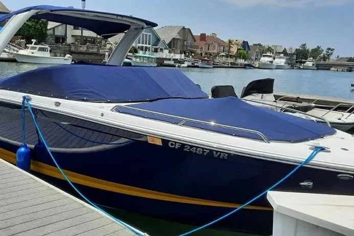 Slide: The Image of 2018 Chaparral 267 SSX boat docked with blue cover in a marina setting. - 7
