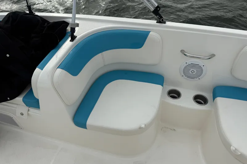 Slide: The Image of 2022 Bayliner Element E18 boat interior with blue and white seating, cup holders, and speaker. - 16