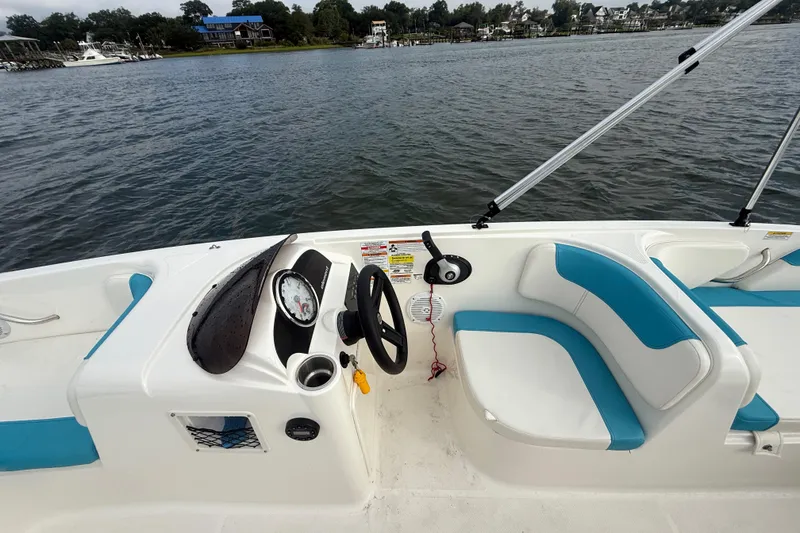 Slide: The Image of 2022 Bayliner Element E18 boat interior with steering wheel and seating, on a calm lake. - 17