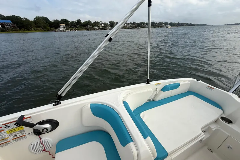 Slide: The Image of 2022 Bayliner Element E18 boat interior with blue and white seating on a calm lake. - 18