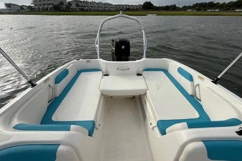 Slide: The Image of 2022 Bayliner Element E18 boat interior with blue and white seating on calm water. - 20
