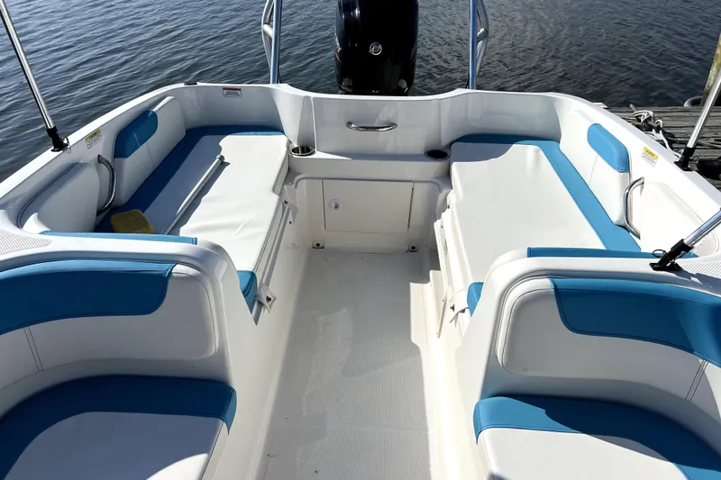 Slide: The Image of 2022 Bayliner Element E18 boat interior with blue and white seating, docked on water. - 34