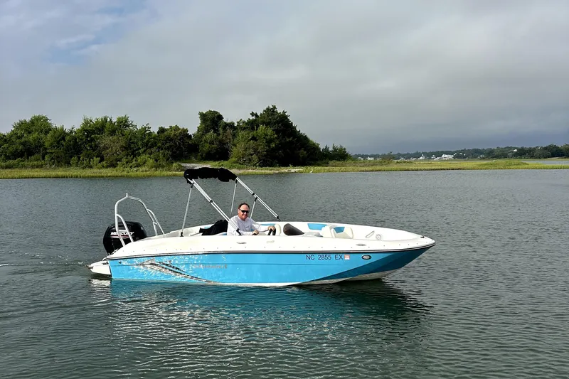 Slide: The Image of 2022 Bayliner Element E18 boat cruising on a calm lake with lush greenery. - 4