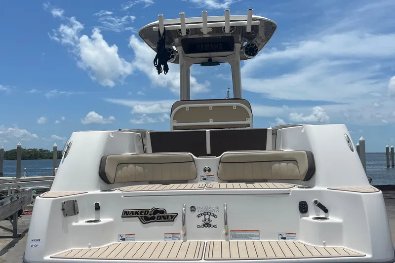 Slide: The Image of 2022 Yamaha Boats 252 FSH Sport docked, showcasing rear seating and deck under clear skies. - 3