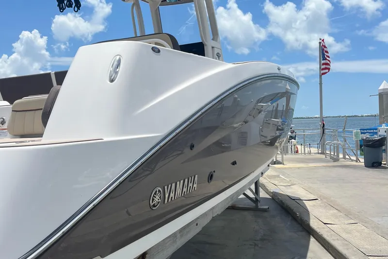 Slide: The Image of 2022 Yamaha Boats 252 FSH Sport docked, showcasing sleek design under a clear blue sky. - 4
