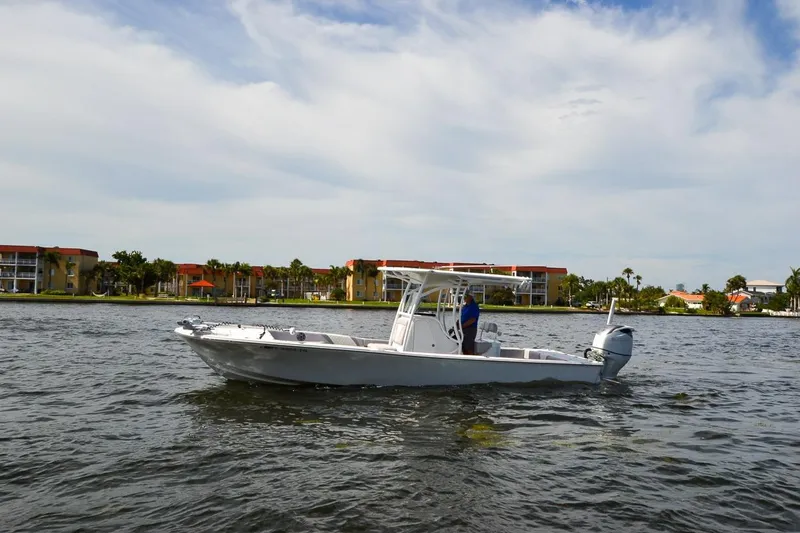 Slide: The Image of 2020 Canyon Bay 28h boat cruising on a scenic waterfront with buildings in the background. - 19