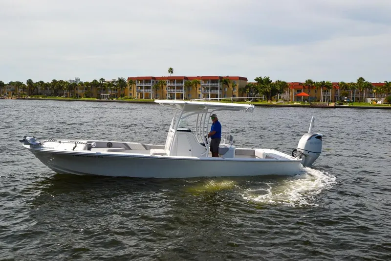 Slide: The Image of 2020 Canyon Bay 28h boat cruising on a scenic waterfront with buildings in the background. - 23