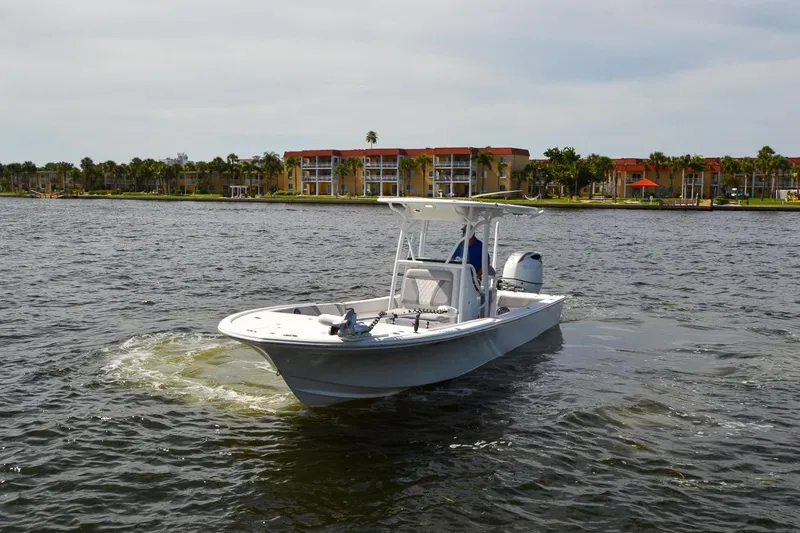 Slide: The Image of 2020 Canyon Bay 28h boat cruising on a scenic waterfront with buildings in the background. - 24