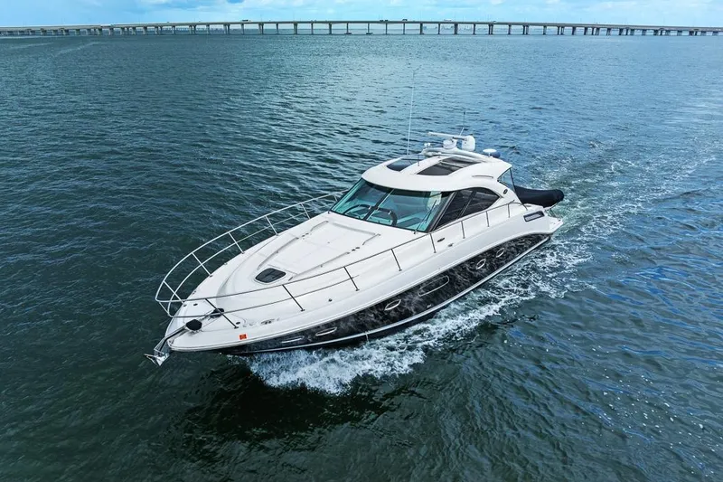 Slide: The Image of 2012 Sea Ray 470 Sundancer yacht cruising on open water with bridge in background. - 37