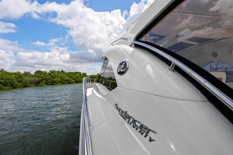 Slide: The Image of 2012 Sea Ray 470 Sundancer yacht cruising on a scenic waterway under a cloudy sky. - 48