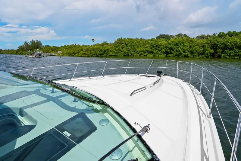 Slide: The Image of 2012 Sea Ray 470 Sundancer yacht cruising on a scenic river with lush greenery. - 50