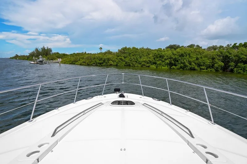 Slide: The Image of Bow view of 2012 Sea Ray 470 Sundancer cruising near lush green shoreline. - 51