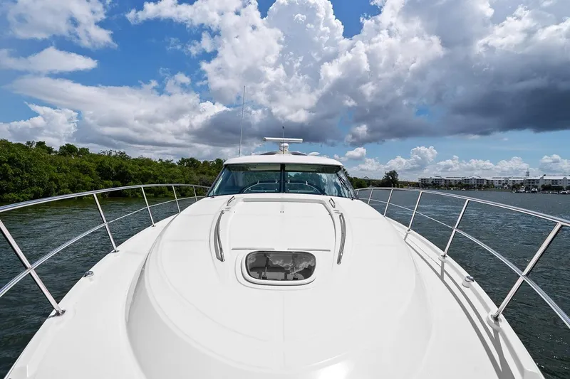 Slide: The Image of 2012 Sea Ray 470 Sundancer yacht cruising on a scenic waterway under a partly cloudy sky. - 52