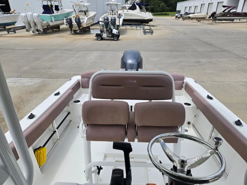 Slide: The Image of 2019 Sea Hunt 225 Ultra boat interior with steering wheel and seating, in a marina setting. - 6