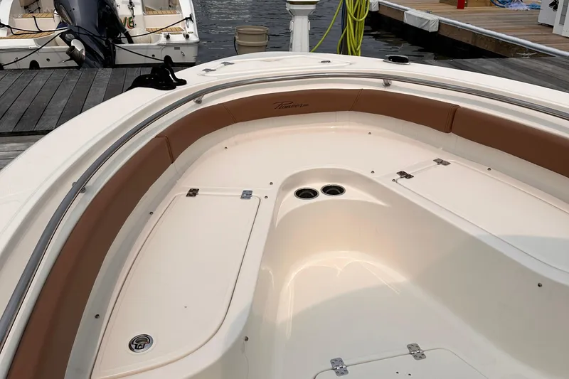 Slide: The Image of 2024 Pioneer 222 Islander boat interior with tan seating and storage compartments at a dock. - 2