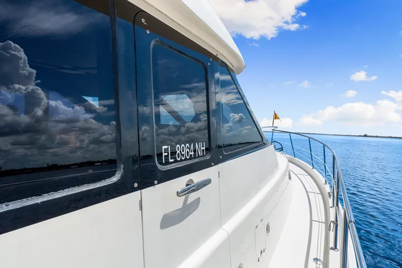Slide: The Image of 2007 Hampton 558 Pilothouse yacht cruising on a sunny day, reflecting clouds on windows. - 58
