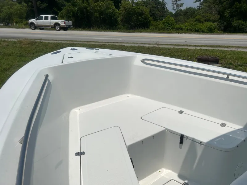 Slide: The Image of 2004 Sailfish 236 CC boat interior with open storage compartments, parked near a road. - 11