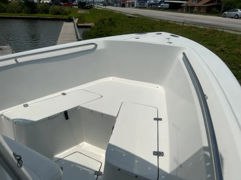 Slide: The Image of 2004 Sailfish 236 CC boat interior with seating and storage, docked near a road. - 12