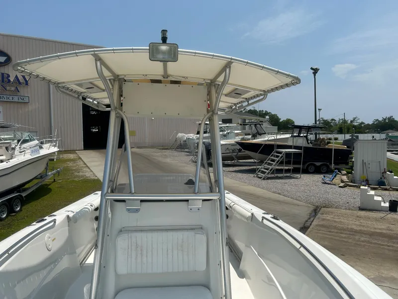 Slide: The Image of 2004 Sailfish 236 CC boat at a marina, featuring a T-top and clear sky. - 16