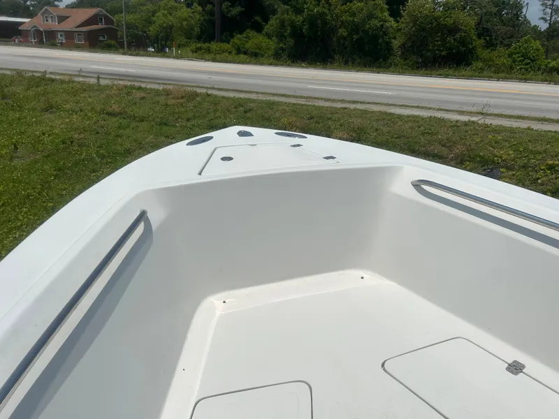 Slide: The Image of 2004 Sailfish 236 CC boat deck, white interior, parked near a road and greenery. - 9