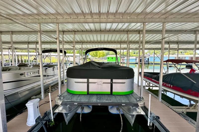 Slide: The Image of 2023 Qwest LT 820 pontoon boat docked in a covered marina. - 1