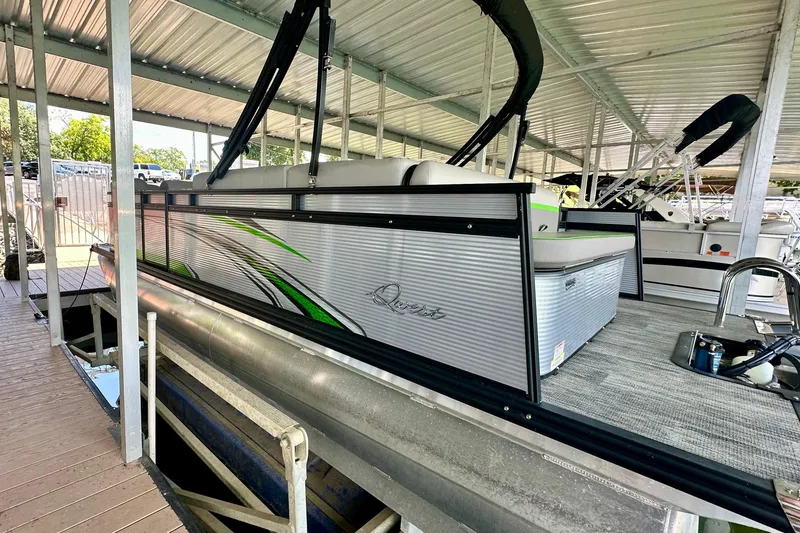 Slide: The Image of 2023 Qwest LT 820 pontoon boat docked under a covered marina. - 2
