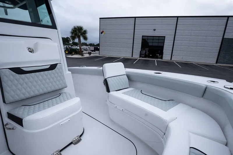 Slide: The Image of 2026 Blackfin 262 HB boat interior with cushioned seating, parked near a modern building. - 45