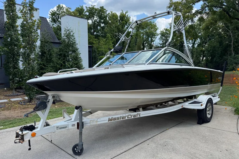 Slide: The Image of 2002 MasterCraft ProStar 209 boat on trailer, parked outdoors with trees in background. - 1