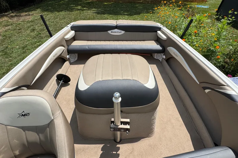 Slide: The Image of 2002 MasterCraft ProStar 209 boat interior with beige and gray seating, surrounded by greenery. - 18