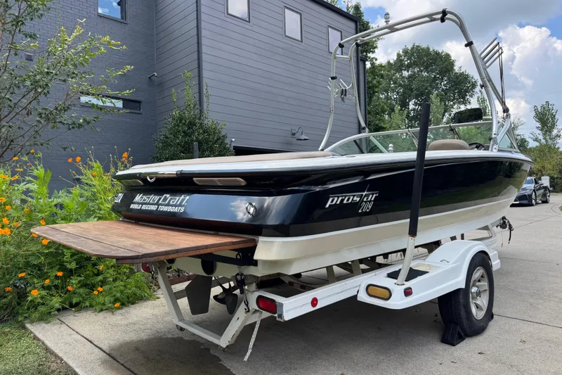 Slide: The Image of 2002 MasterCraft ProStar 209 boat on trailer, parked near modern building. - 3