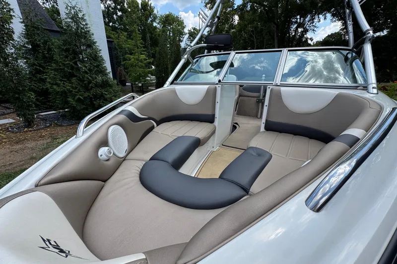 Slide: The Image of 2002 MasterCraft ProStar 209 boat interior with beige seating and speaker, surrounded by trees. - 7