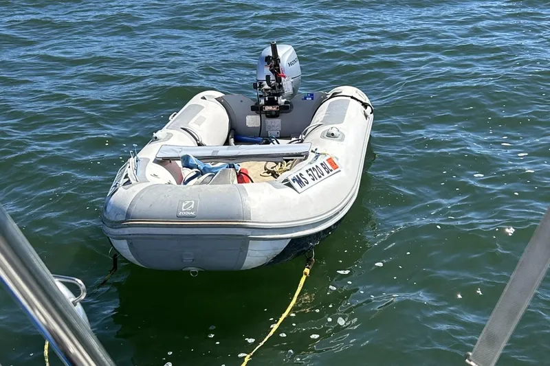 Slide: The Image of Inflatable Zodiac boat with Honda outboard motor on water, tied to Pearson 39-2 sailboat. - 21