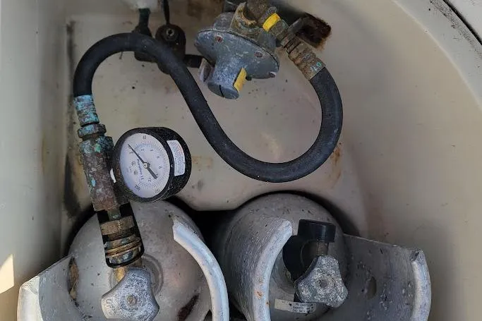 Slide: The Image of Two propane tanks with hoses and gauge in a Pearson 39-2 boat compartment. - 24